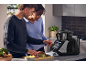 Paar kocht mit einer intelligenten Küchenmaschine, bereitet Gemüse zu.