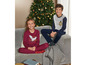 Zwei Kinder in Harry Potter-Pyjamas sitzen auf einem Sofa vor einem Weihnachtsbaum.