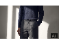 Mann in dunkelblauem Pullover, grauer Hose und schwarzem Ledergürtel