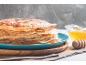 Stapel Pfannkuchen auf blauem Teller mit Honig und Honiglöffel aus Holz.