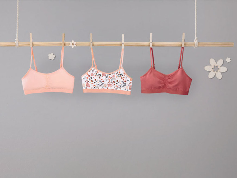 Drei Sport-BHs, darunter einer mit Blumenmuster.