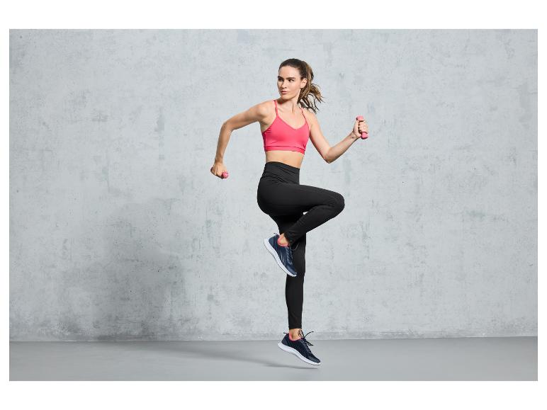 Eine Frau in Sportkleidung trainiert mit Hanteln.