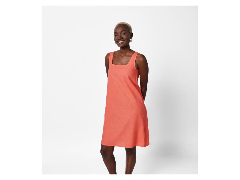 Model trägt ein kurzes, korallenfarbenes Kleid.