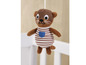 Ein brauner Plüschotter mit gestreiftem Outfit, hängend über einem Babybett.