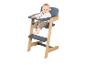 Lächelndes Baby sitzt in einem Hochstuhl aus Holz und Grau.