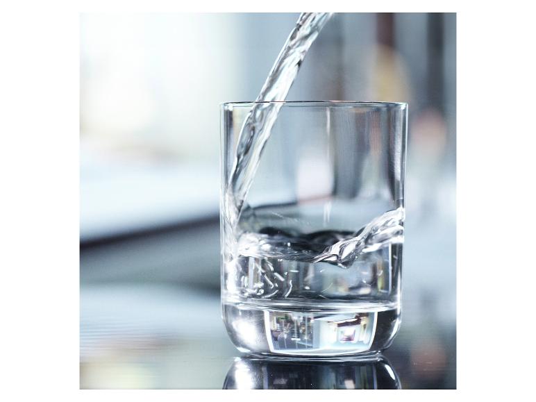 Wasser wird in ein Glas gegossen, mit Reflexionen auf der Oberfläche.