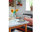 Spielzeug-Sonnenblumen in einer Glasvase auf einem Couchtisch mit Büchern und Sofa.