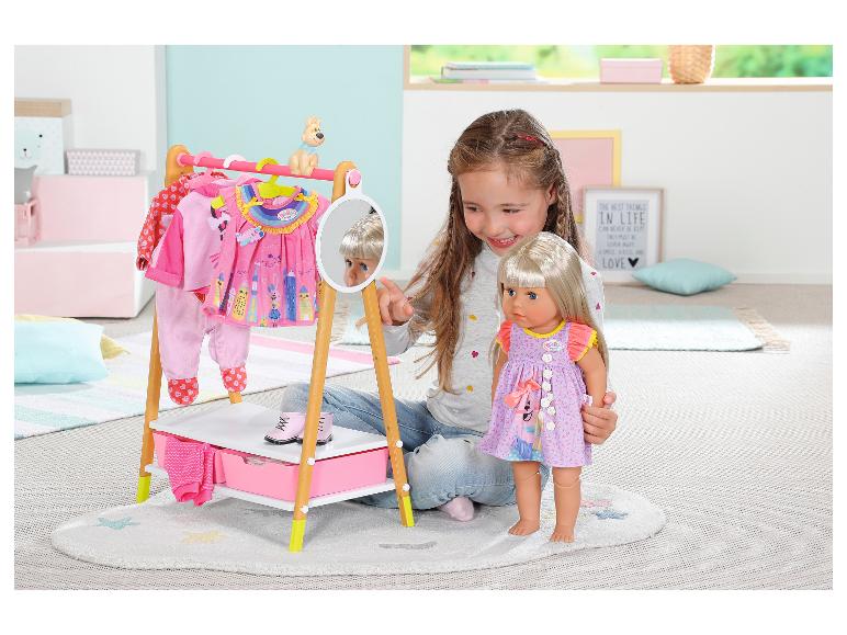 Mädchen spielt mit BABY born Puppe und Kleiderständer mit Puppenkleidung.