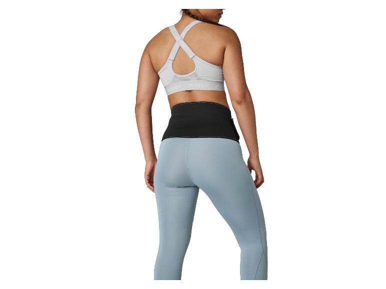 Frau in grauem Sport-BH, schwarzem Fitnessgürtel und blauen Leggings, Rückansicht.