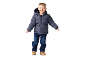 Lächelnder Junge in dunkelblauer Steppjacke, Jeans und braunen Stiefeln.