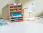 Ein Holz-Organizer mit Stiften, Notizbüchern und einer weißen Schreibtischlampe.