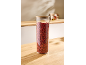 Vorratsglas mit Holzdeckel gefüllt mit getrockneten Goji-Beeren auf einem Holztisch.