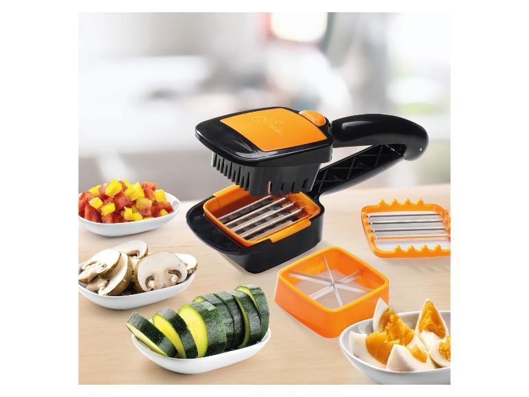 Schwarz-orangefarbener Gemüseschneider mit Zubehör und geschnittenem Gemüse in Schalen.