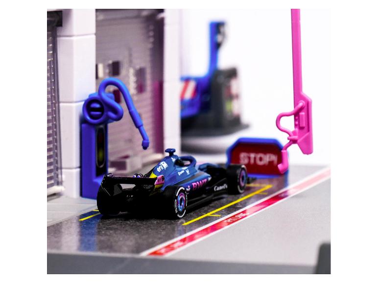 Blauer Rennwagen im Boxenstopp mit einem „STOP“-Schild und Tankausrüstung.