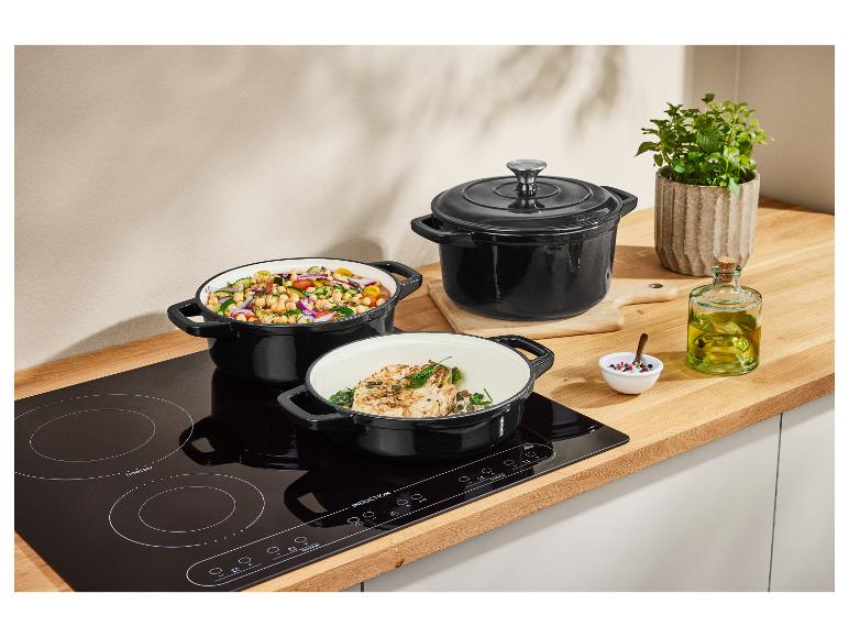 Drei schwarze Gusseisen-Töpfe auf einem Induktionskochfeld.