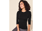 Lächelnde Frau in schwarzem Langarmshirt und grauen Leggings.