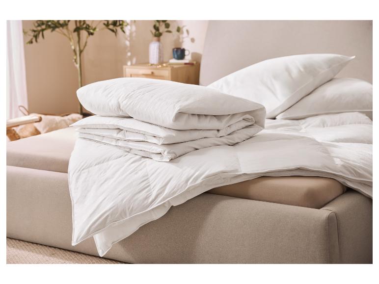 Weiße Kissen und Bettdecken ordentlich auf einem Bett in einem hellen Raum gestapelt.