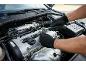 Mann in Handschuhen repariert Automotor mit einem Ratschenschlüssel.