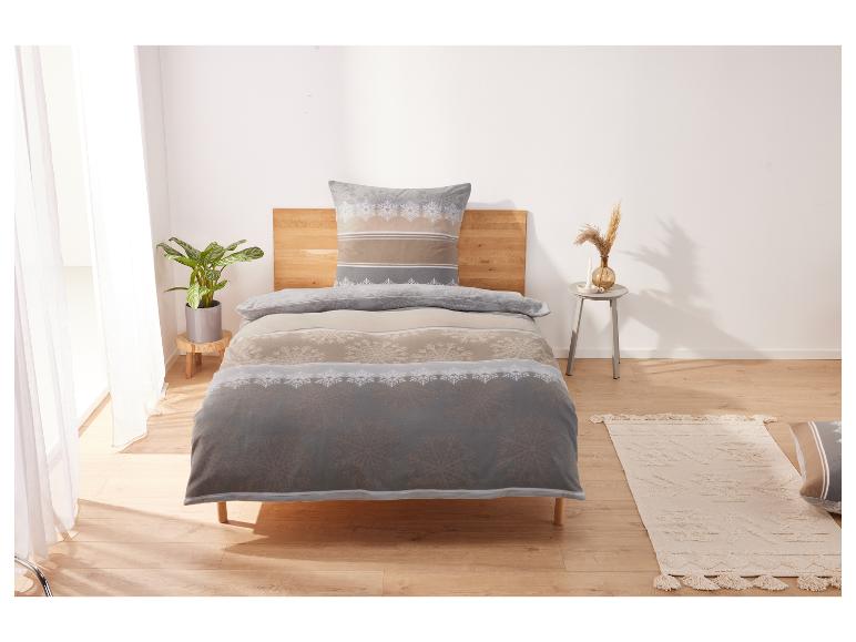 Ein Bett mit einer Bettdecke mit Schneeflockenmuster in Grau- und Beigetönen.