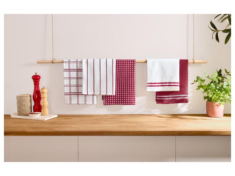 Rot-weiße Küchentücher hängen an einer Holzstange in einer Küche.