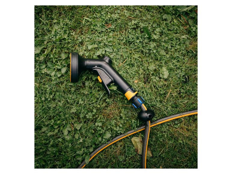 Schwarze Gießpistole mit gelben Akzenten und Gartenschlauch auf Gras.