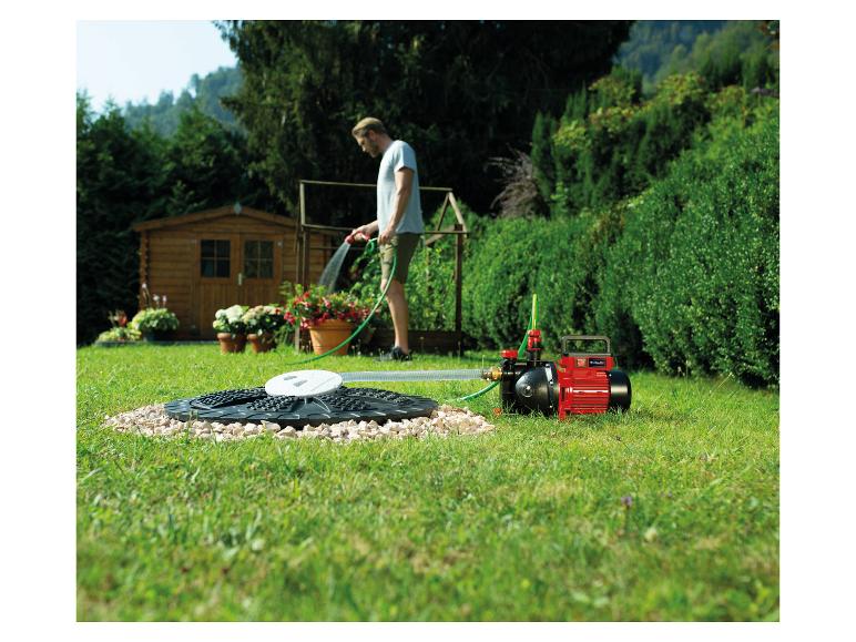 Mann bewässert Garten mit Wasserpumpe und unterirdischem Wassertanksystem.