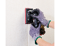 Hände in Schutzhandschuhen bedienen einen Akku-Schwingschleifer an einer Wand.
