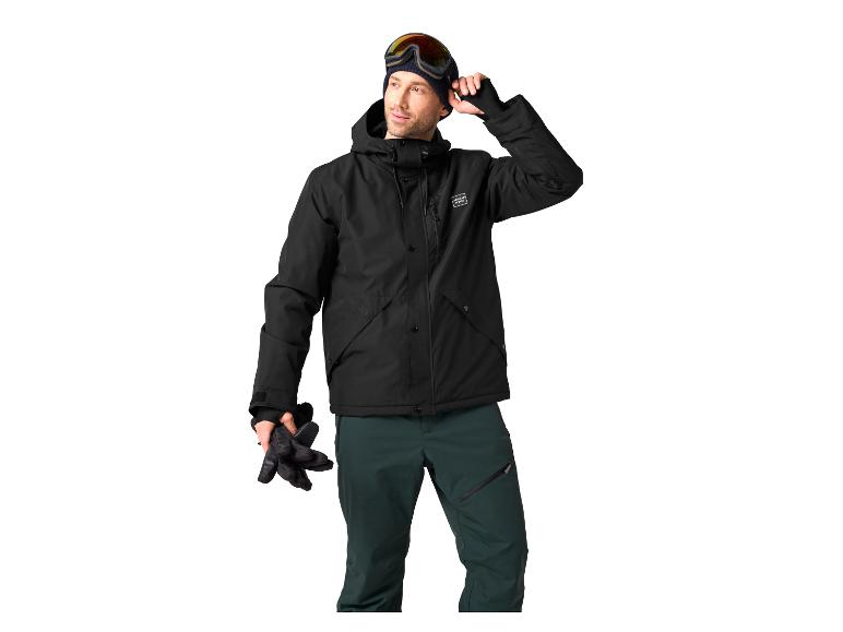 Mann in schwarzer Skijacke, grüner Hose und Skibrille.