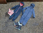 Zwei blaue Regenanzüge mit Kapuze und rosa und schwarze Gummistiefel.