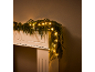 Weihnachtsgirlande mit warmweißen LED-Lichtern auf einem weißen Kaminsims.