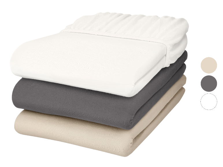 Drei gefaltete Spannbettlaken: weiß, grau und beige, mit Farbmustern.