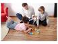 Familie spielt auf dem Boden mit Buchstabenblöcken und Karten.