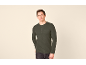 Mann in grünem Langarmshirt mit Knöpfen und Tasche, posiert vor hellem Hintergrund.