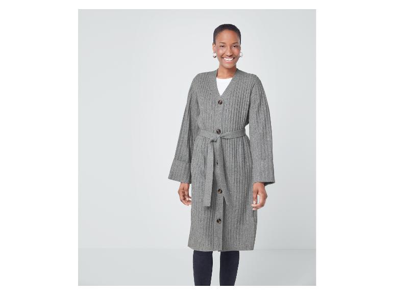 Eine Frau trägt einen grauen Strickcardigan mit Gürtel.