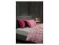 Schlafzimmer mit einem Bett mit rosa Kissen und einem rosa gemusterten Bettbezug.