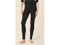 Frau in schwarzen Leggings und schwarzem Oberteil, barfuß stehend.