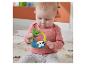 Sitzendes Baby spielt mit einer bunten Faultier-Rassel.