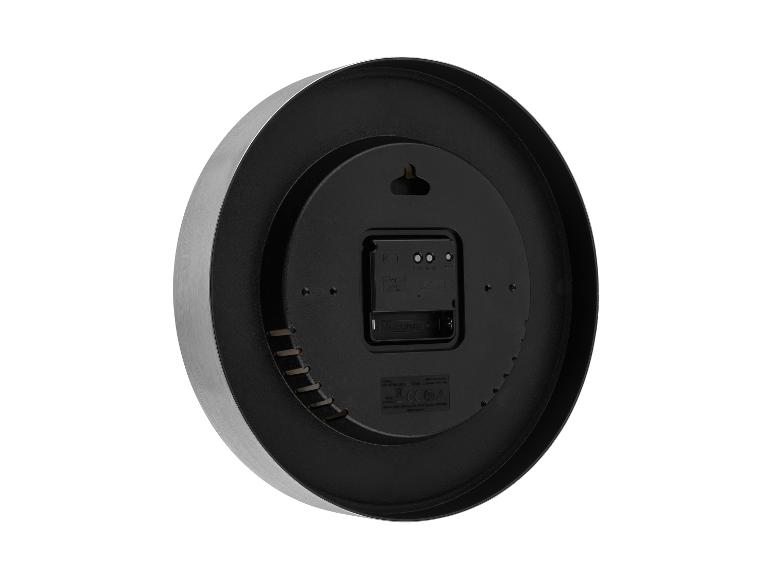 Rückansicht einer runden Wanduhr mit gebürstetem Metallrahmen und schwarzer Kunststoffrückseite, die das Batteriefach und die Einstellungen zeigt.