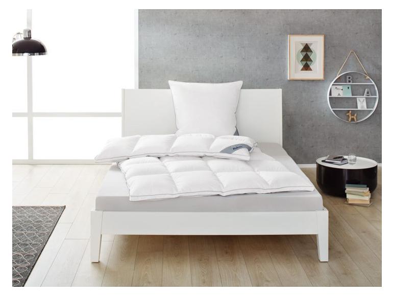 Bett mit weißer Bettwäsche und Daunendecke in einem modernen Schlafzimmer.