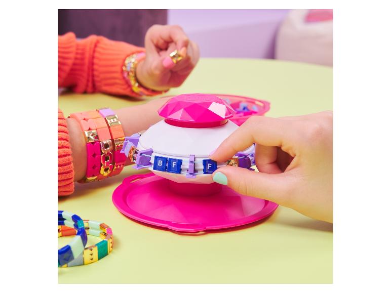 Ein rosa Armbandmacher mit Perlen und einem Stapel bunter Armbänder.