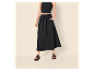Frau in schwarzem Crop-Top, schwarzem Maxirock mit Taschen und schwarzen Sandalen.