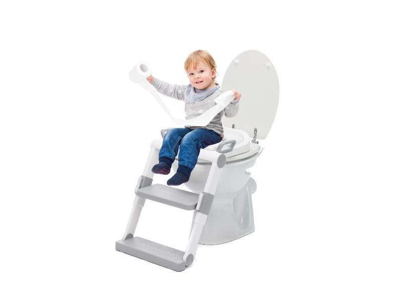 Lächelndes Kleinkind sitzt auf einem Toilettensitz mit Treppe und hält Toilettenpapier.