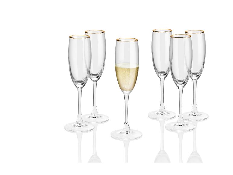 Ein Set Champagnergläser mit goldenem Rand, eines davon ist gefüllt.