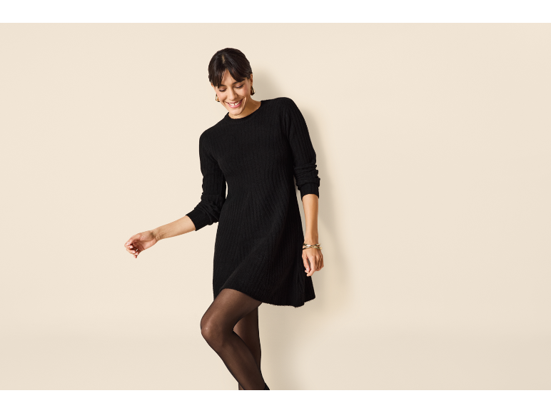 Frau in einem schwarzen Strickkleid und schwarzer Strumpfhose