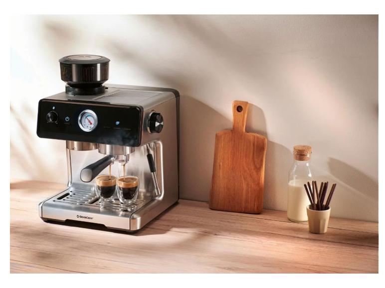 Espressomaschine brüht Kaffee in zwei Gläser, mit Milch und einem Schneidebrett daneben.