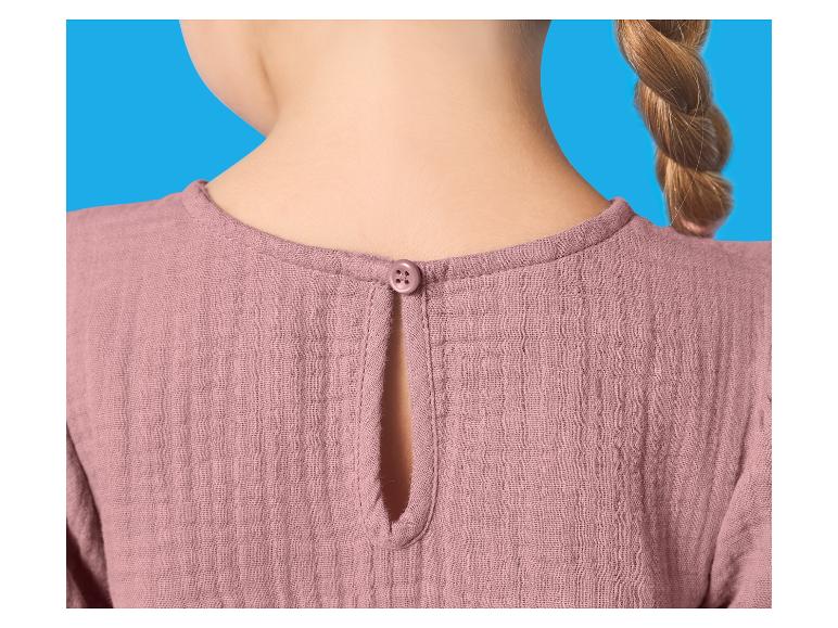 Rücken einer rosa Kinderbluse mit Knopf am Hals und Zopf