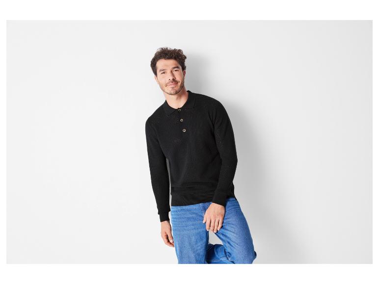 Mann trägt einen schwarzen Pullover mit langen Ärmeln und blaue Jeans.