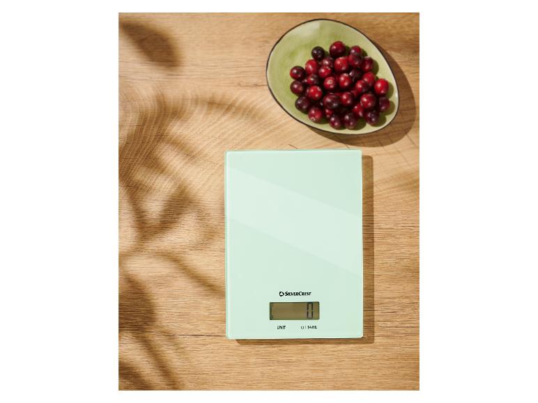 Eine SilverCrest Küchenwaage auf einem Holztisch mit einer Schale Cranberries.