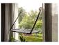 Katzenfensterbett mit Saugnäpfen am Fenster, mit grünen Bäumen im Hintergrund.