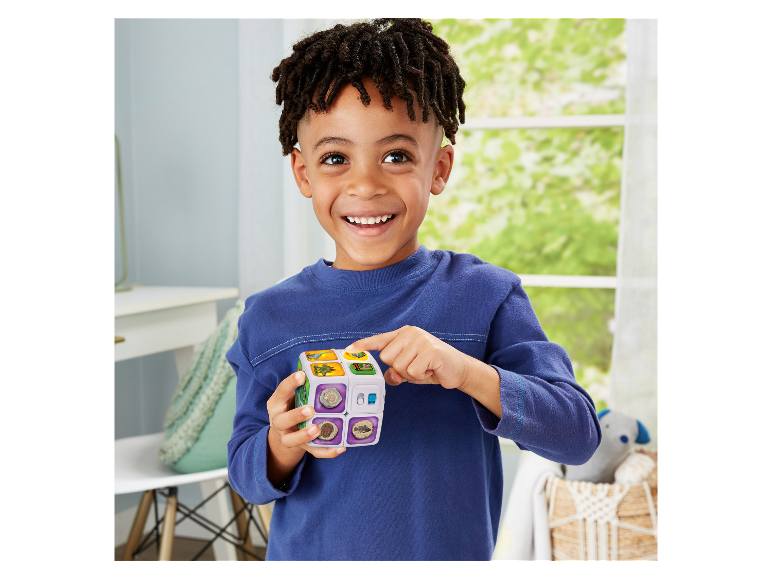 Kind spielt mit einem interaktiven Würfel mit Dinosaurier- und Fossilbildern.